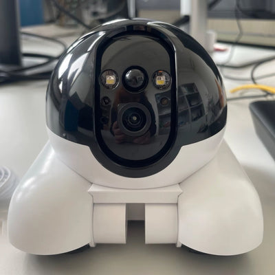 White and black security camera on a desk with blurred background